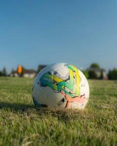 Soccer ball resting on a grassy field under clear blue sky